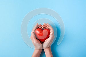 Big red heart in women`s hands on a blue background. Copy space