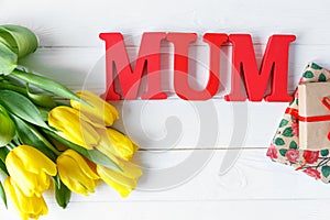 Big red letters Mum lies on the table with gift card and flowers. Mother`s day concept. top view