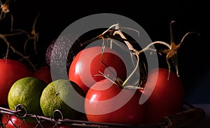 Big red and ripe tomatoes in an old basket on black background