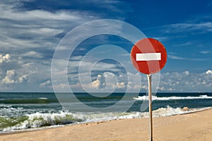 Big red road prohibiting stop sign standing on a deserted beach