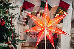 Big red seven pointed Christmas star on the Christmas tree and the fireplace.