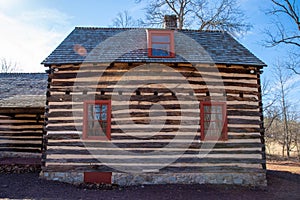 Big red windows in historical log cabin reflecting trees.