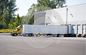 Big rig day cab semi trucks for local deliveries loading and unloading commercial cargo in warehouse dock