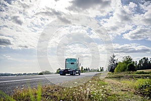 Big rig green classic semi truck tractor running to warehouse for picking up loaded semi trailer for next delivery