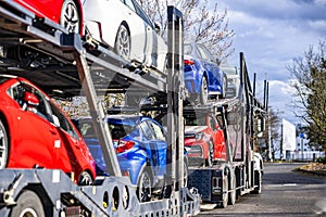 Big rig industrial car hauler semi truck with two loaded semi trailers standing on the parking lot for truck driver resting