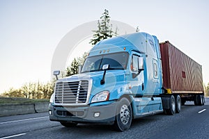 Big rig long haul semi truck transporting container on the highway photo