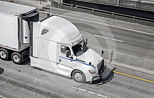 Big rig long haul semi truck transporting food in refrigerated semi trailer running on the wide highway road