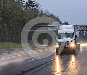 Big rig long haul semitruck transporting cargo in semi trailer running on wet sleep night road with rain dust