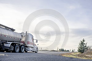 Big rig low roof semi truck transporting liquid cargo in tank semi truck moving on the flat road