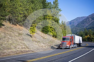 Big rig orange semi truck carry bulk semi trailer driving on win