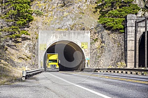 Big rig professional yellow semi truck going through the tunnel
