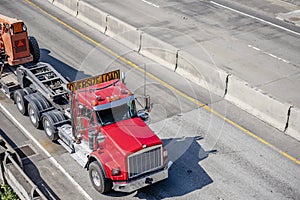 Big rig red semi truck with oversize load sign on the roof transporting oversized equipment on the semi trailer