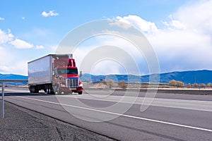 Big rig red semi truck with refrigerated semi trailer transporting commercial cargo on flat road in Utah