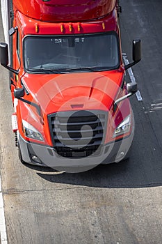 Big rig red semi truck tractor with semi trailer driving on the wide road