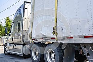 Big rig semi truck with broken dry van semi trailer standing on the city street waiting for possible repair or replacement of