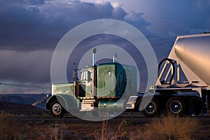 Big rig semi truck with bulk semi trailer carries cargo on the A