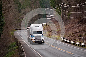 Big rig semi truck with bulk semi trailer moving by winding road