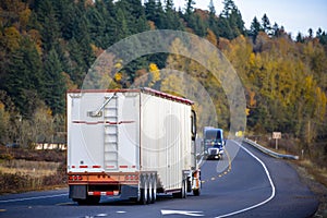 Big rig semi truck with covered bulk semi trailer driving on the winding autumn road ÐºÐ³Ñ‚Ñ‚ÑˆÑ‚Ð¿ towards another semi truck