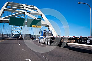 Big rig semi truck with flat bed trailer driving over arched Fremont bridge