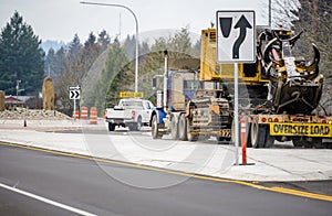 Big rig semi truck with oversize load sign on the roof transporting oversized load on the semi trailer turning on the round road