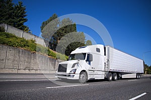 Big rig semi truck with reefer semi trailer going on highway wit photo