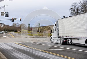 Big rig semi truck with reefer semi trailer transporting frozen food on the city road
