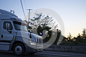 Big rig semi truck tractor driving on evening road with turn on