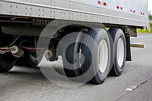 Big rig semi truck transporting cargo in dry van semi trailer with two axles running on the wide highway road