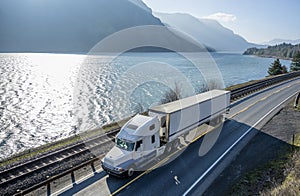 Big rig semi truck transporting cargo in refrigerator semi truck running on the road along Columbia River