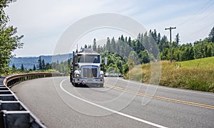 Big rig semi truck transporting flammable liquids and fuel in tank semi trailers running on the winding road