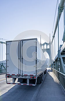 Big rig semi truck transporting semi trailer driving on the arch bridge