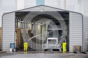 Big rig semi truck washes in covered car wash station with manual washing