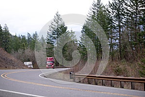 Big rig semi trucks convoy going up hill on the winding mountain