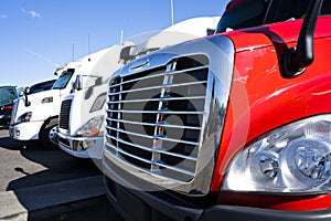 Big rig semi trucks of different make and model standing in row on the truck stop