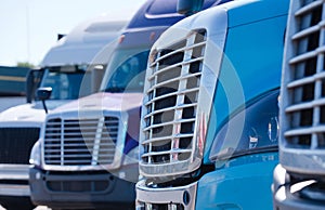 Big rig semi trucks tractors grilles in row on truck stop