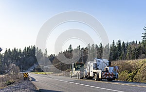 Big rig towing semi truck tow another broken big rig semi truck with application running on the road with hill and trees photo