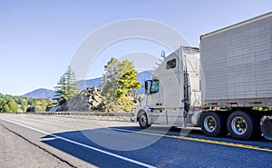 Big rig white bonnet long haul semi truck transporting frozen food in refrigerator semi trailer running on the road in Columbia