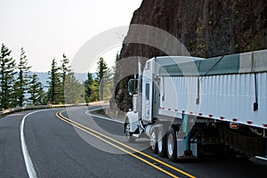 Big rig white semi truck with bulk covered semi trailer running