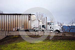 Big rigs semi truck fleets going side by side on the highway exit