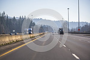 Big rigs semi trucks and another cars traffic in both directions on divided highway