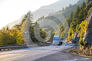 Big rigs semi trucks convoy turning on the sunny autumn road in