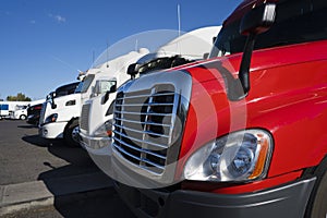 Big rigs semi trucks in row on truck stop part of cabs view