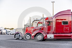 Big rigs semi trucks standing in row on truck stop parking lot for resting and waiting for the continuation of the route according