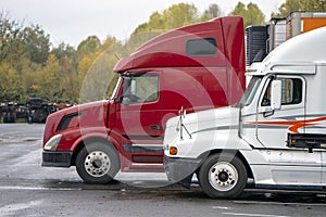 Big rigs semi trucks with trailers stand on the parking lot in r