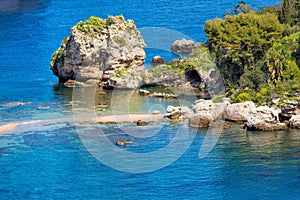 Big rock and narrow path connecting Isola Bella island to mainland Taormina beach, Sicily, Italy