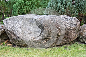 Big rock or stone on the green grass in the garden.