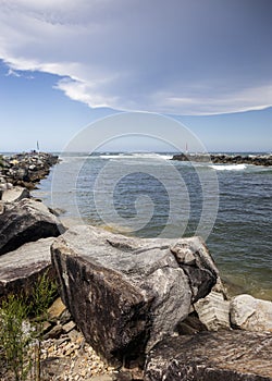 Big rocks and ominous storm clouds in sky over water at breakwall on Wooli Wooli River in Australia photo