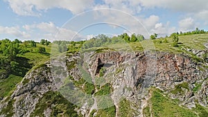 Big rocky cliff and cave in it. The camera is approaching from afar.