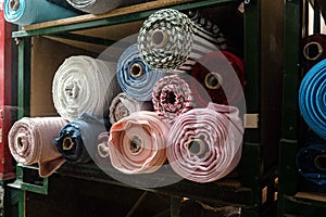 Big rolls of colorful fabric stacked on factory shelves ready for production