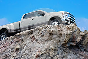 Big rugged pickup truck driving on a rocky cliff ledge